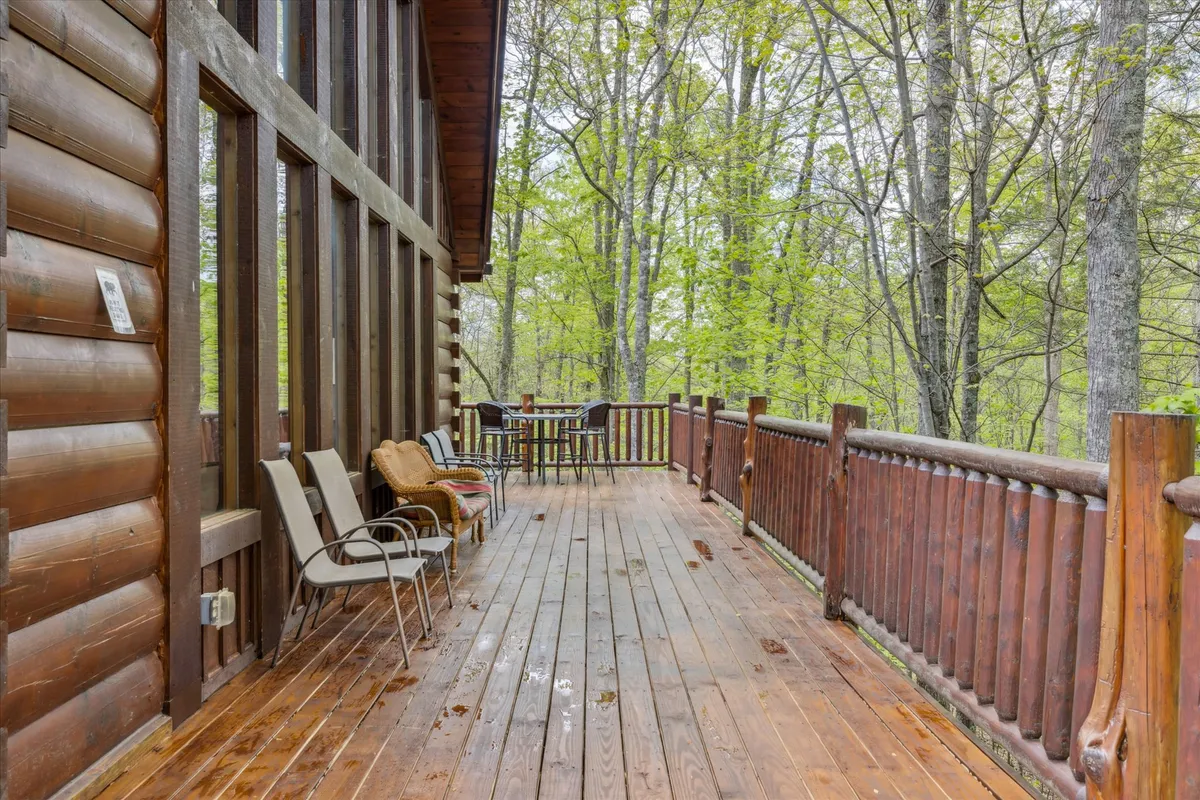A spacious wooden deck with comfortable outdoor furniture, set among lush trees. The open layout encourages gatherings, relaxation, or quiet moments listening to nature, and the deck feels inviting for both families and groups.