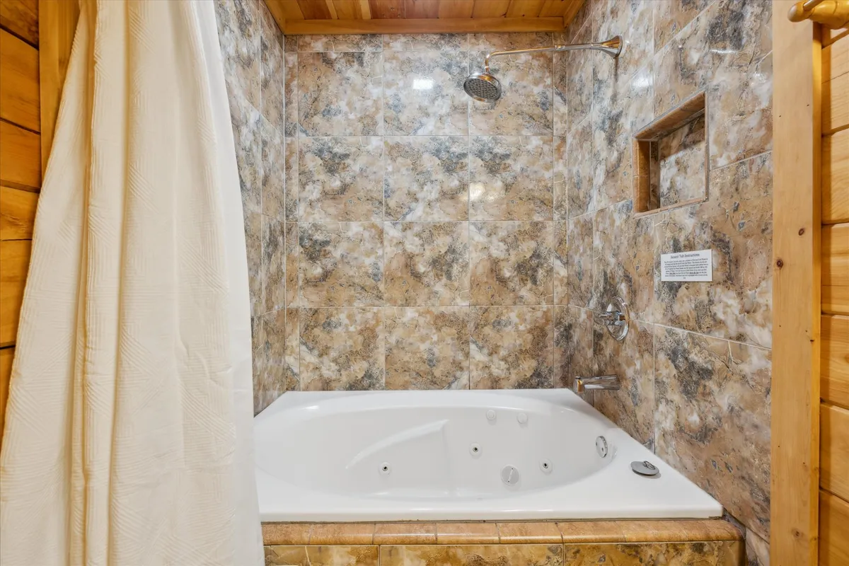 A tranquil interior featuring a jacuzzi tub with textured wall tiles and a wooden ceiling, suggesting a rejuvenating retreat perfect for soothing muscles after outdoor activities.