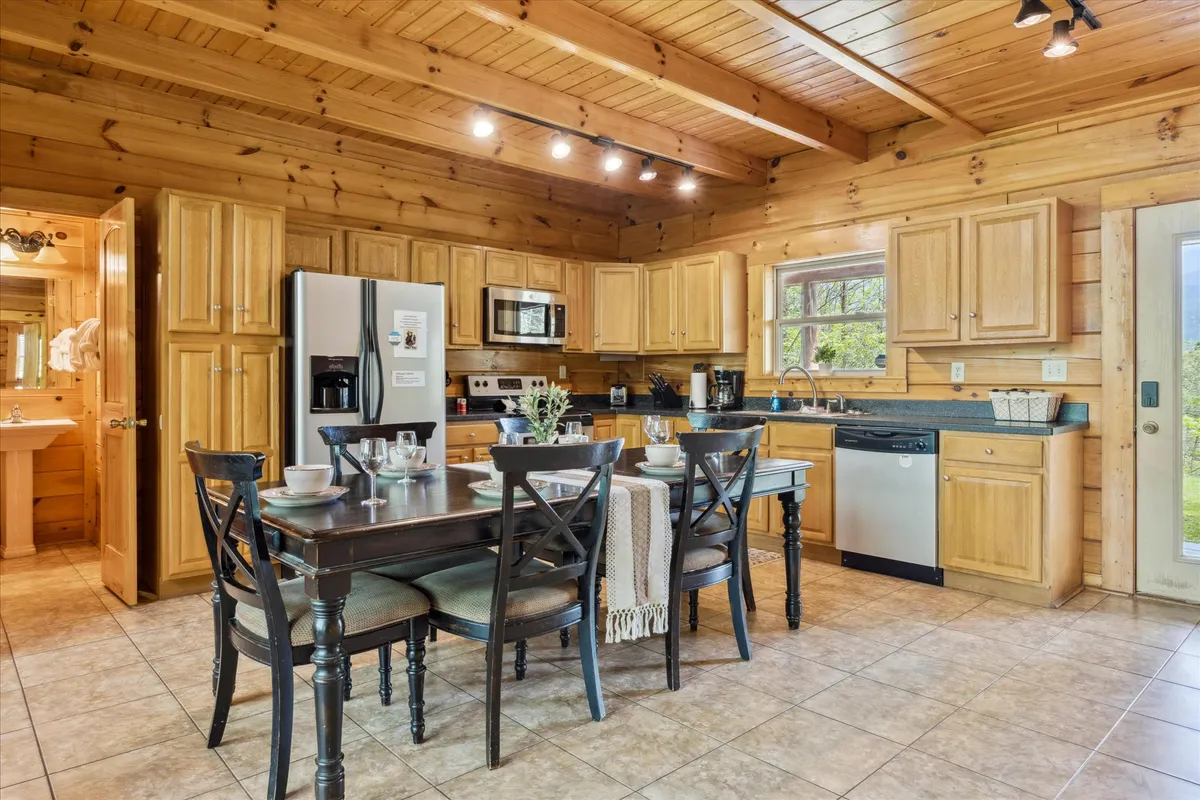 A cozy dining area connected to the kitchen, complete with a dining table, kitchen cabinets, appliances, and a window with a pleasant view. The space is clearly set up for shared meals and togetherness.