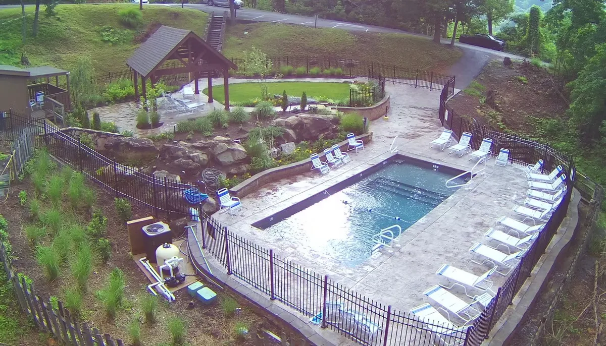 A landscaped resort pool area complete with lounge chairs, a gazebo, and vibrant greenery. The inviting water and lounging spaces highlight the premium amenities available to guests.