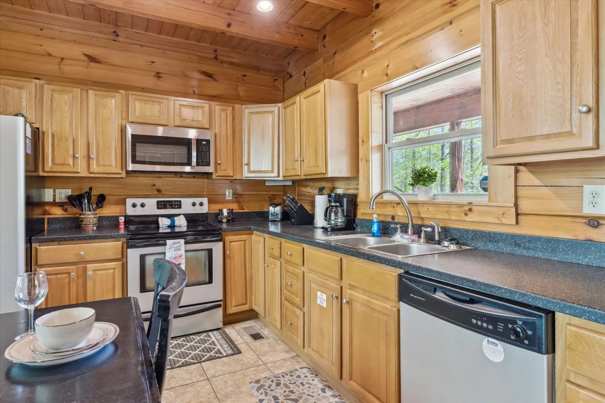 A spacious, inviting kitchen featuring a central island, stainless steel appliances, and wooden cabinets. Natural light pours in from a window above the sink, creating a warm, welcoming space ideal for meal preparation and socializing.