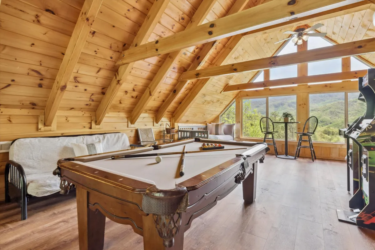 A welcoming game room with a pool table positioned near large windows, providing mountain views. Comfortable seating invites group gatherings, and the setting exudes a casual, friendly, and lively vibe—ideal for friendly competition and socializing after days of exploration.