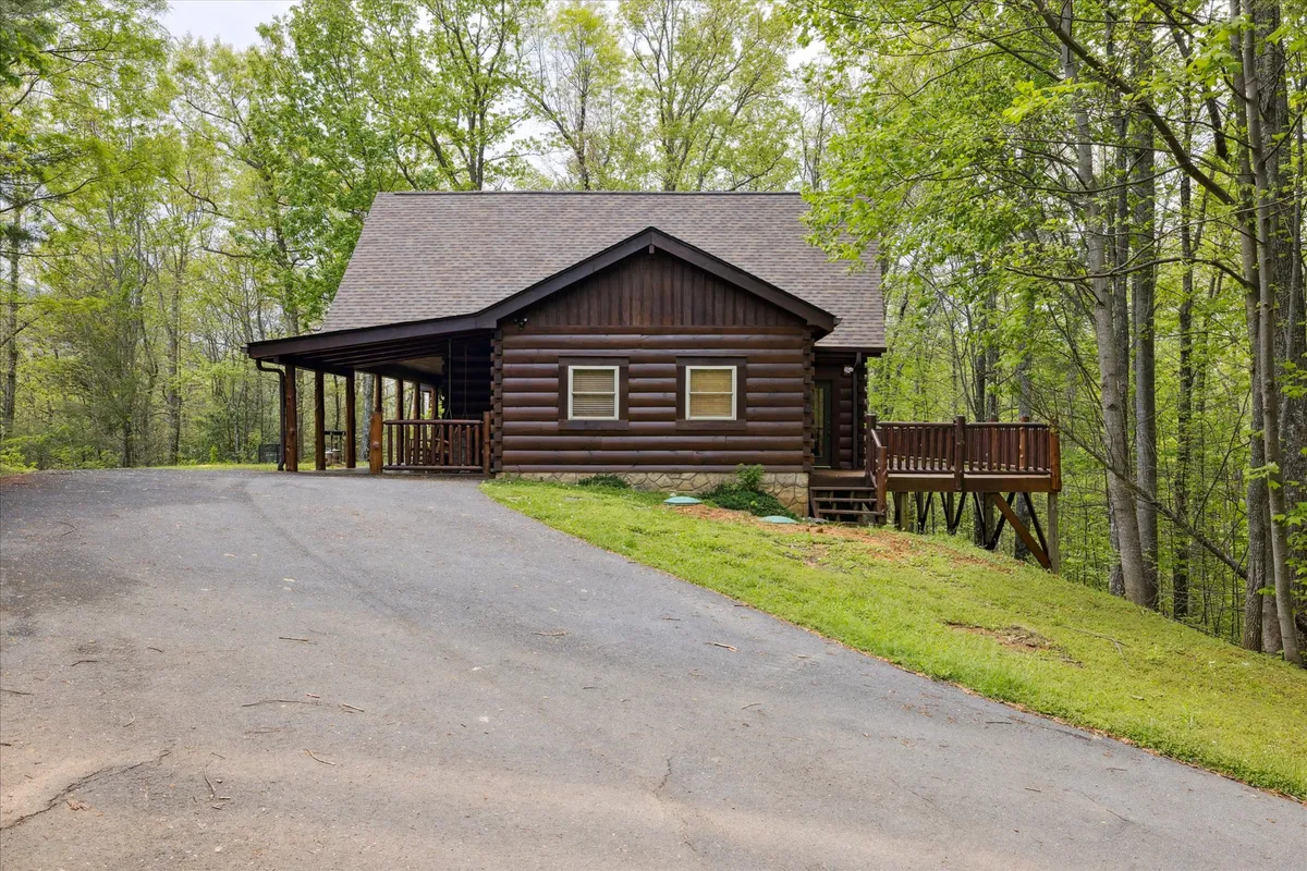 The log cabin is nestled among lush greenery, with a view of its welcoming porch and the surrounding natural landscape. The inviting outdoor space hints at opportunities for nature walks, playtime, and unwinding in a peaceful, forested environment.